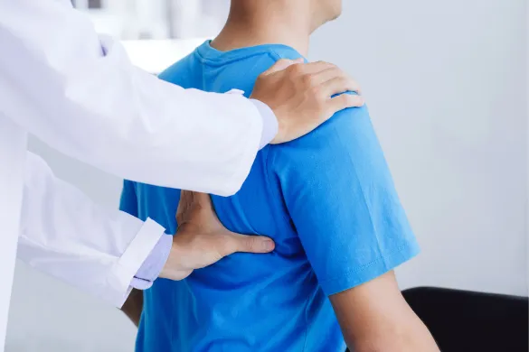 A doctor examining a patient's back and shoulder.