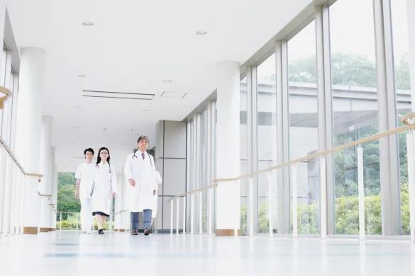 A group of medical professionals walking down a bright, modern hospital hallway.