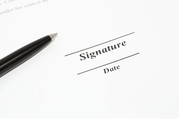 A black pen resting next to a signature and date line on a document.
