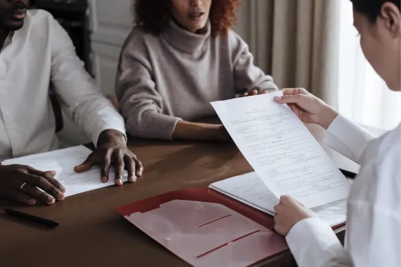 A professional reviewing paperwork with a couple during a meeting.