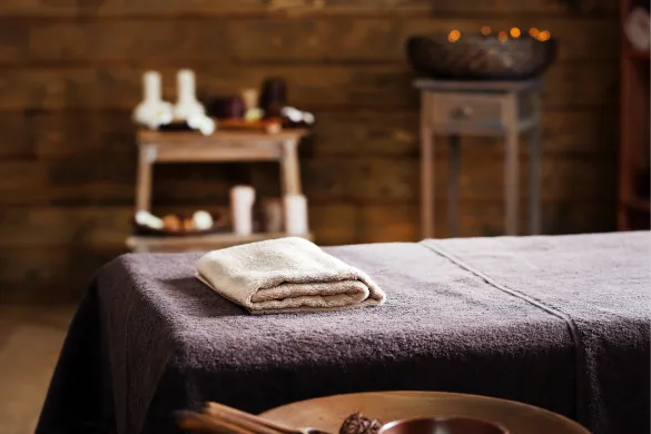 A massage table with a folded towel inside a spa room.