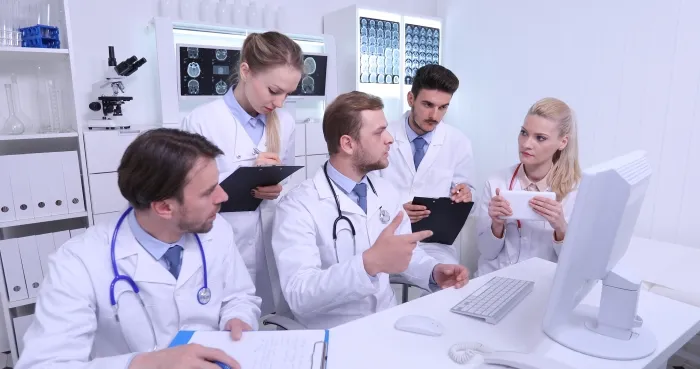 A medical team discussing a case around a computer in an office.