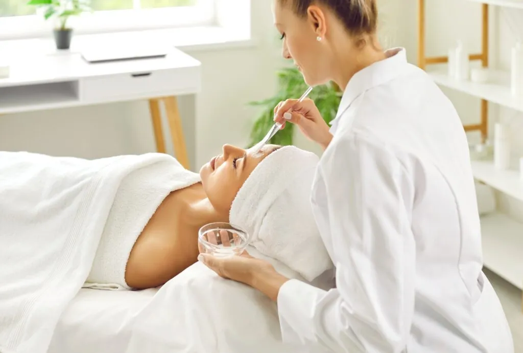 Aesthetician applying a facial mask to a client in a spa.