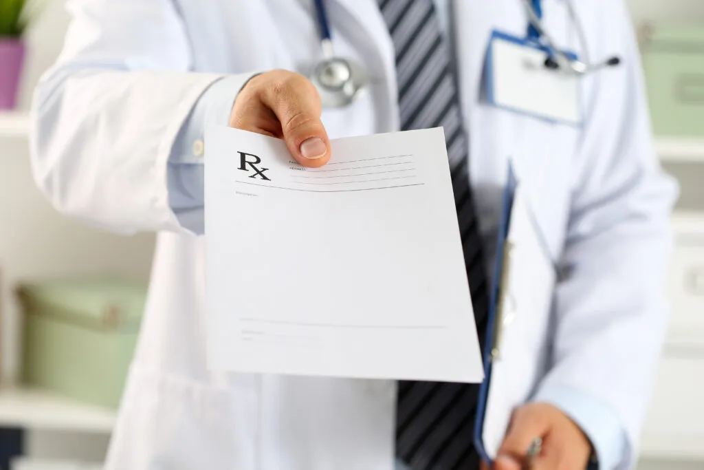 A doctor handing out a prescription pad.